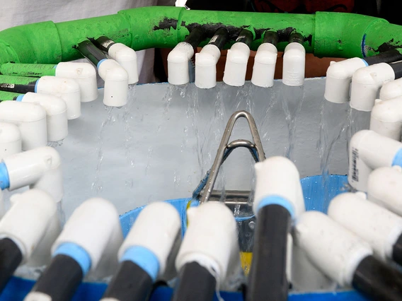 A white tank has a ring of tubes that flow water.
