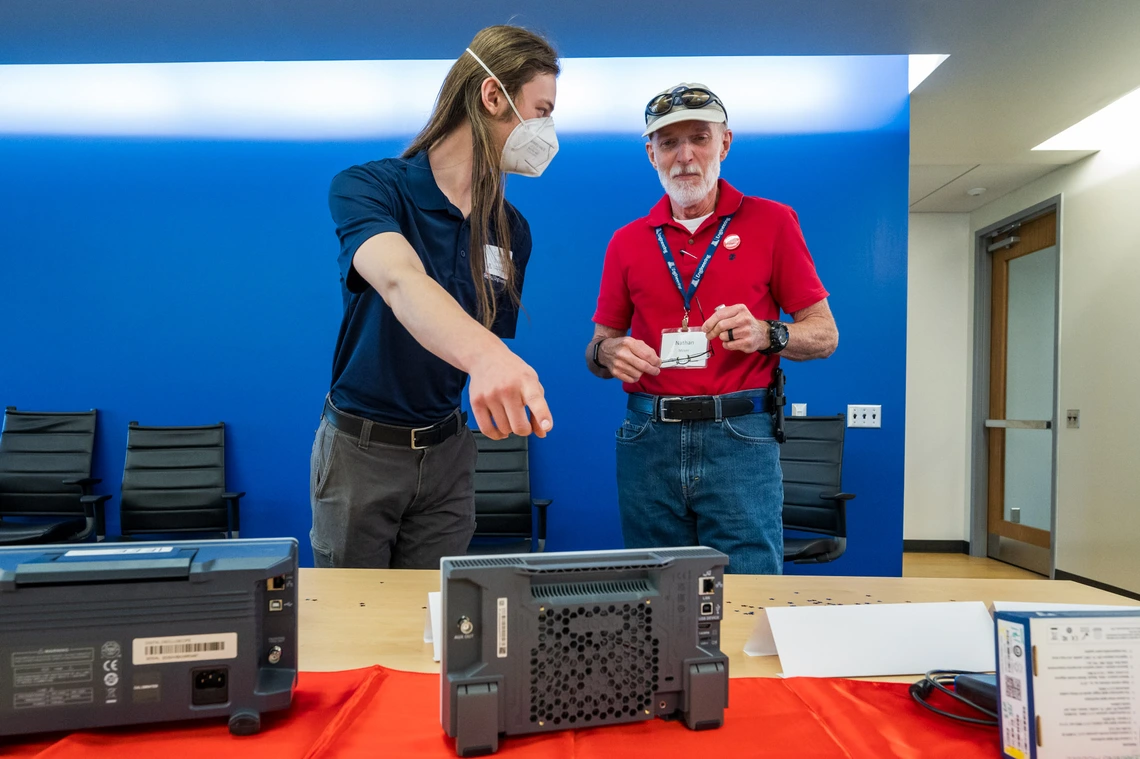 two people talking, one pointing to electrical equipment